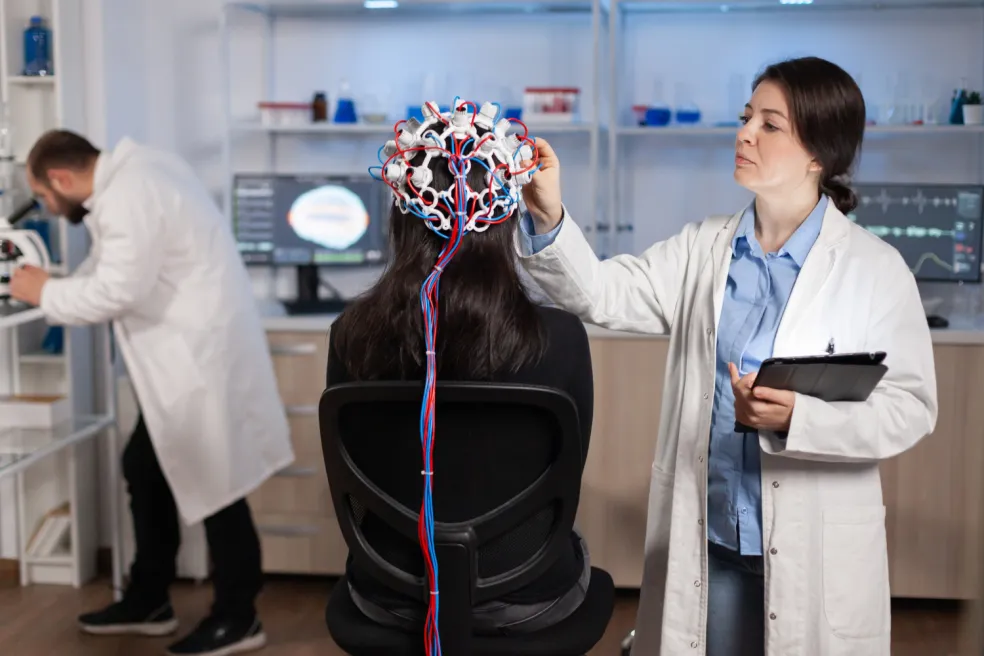 Zdravotníčka kontroluje EEG elektródy na hlave pacientky počas neurologického vyšetrenia