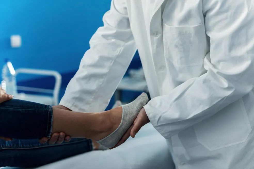 Lekár vyšetruje pacientke poranený členok v ambulancii. Odborné vyšetrenie je dôležité pri silnej bolesti, opuchu alebo podozrení na vyvrtnutie či zlomeninu