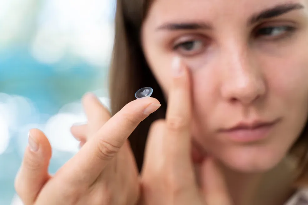 Žena drží kontaktnú šošovku na končeku prsta – pri očnom herpese a iných očných infekciách je potrebné prerušiť nosenie kontaktných šošoviek